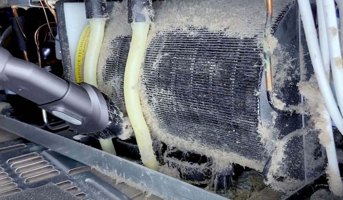 Vacuum brush cleaning dust from refrigerator condenser coils
